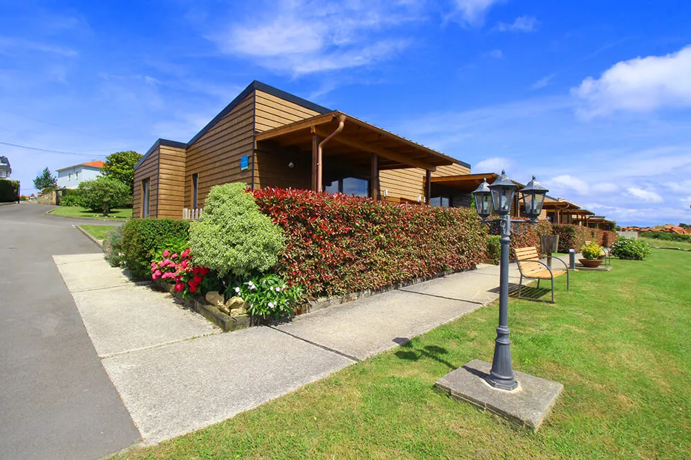 Fila de bungalows de madera con farola y jardín